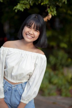 Açık havada duran Asyalı ergenin dişlek gülen yüzü