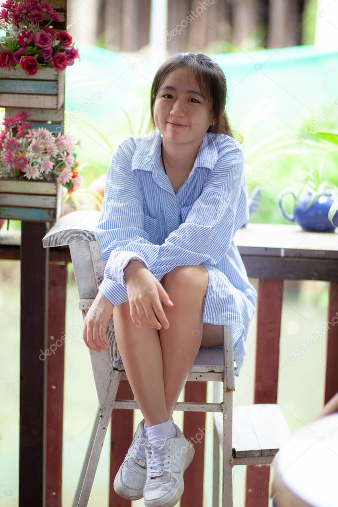 cheerful asian teenager, relaxing on wood desk