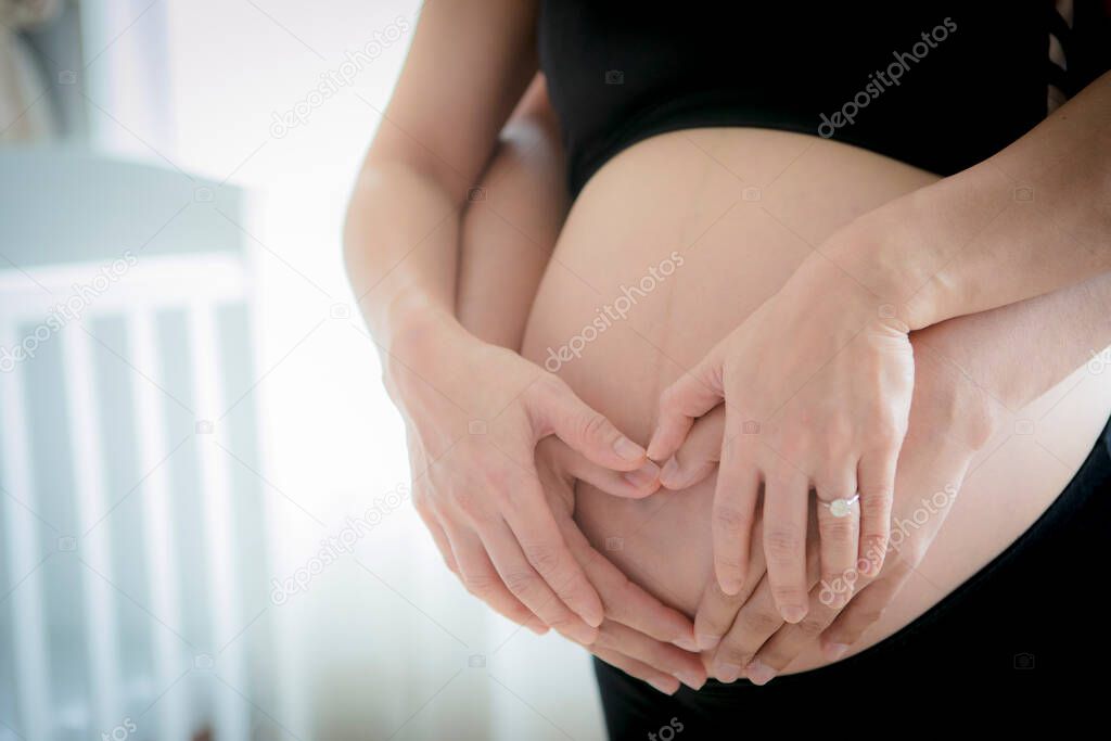 close up on pregnant belly and with husband hand 