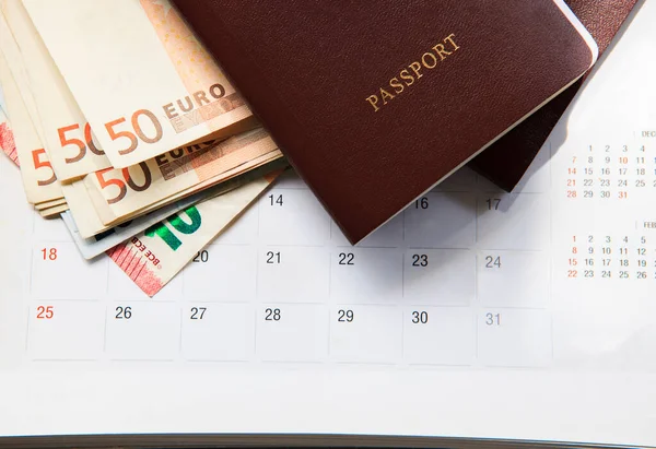 red cover passport book and 50 euro banknote on calendar date