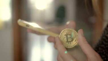 Bir el ve diğer bir bitcoin para holding ile bir smartphone kullanarak. Dünya çapında cryptocurrency ve dijital ödeme sistemi Bitcoin olduğunu.