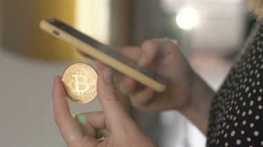 Kadın bir eliyle bir smartphone kullanarak ve bir bitcoin tutan diğer para. Dünya çapında cryptocurrency ve dijital ödeme sistemi Bitcoin olduğunu.