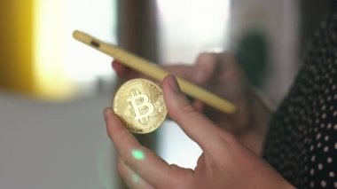 Bir el ve diğer bir bitcoin para holding ile bir smartphone kullanarak. Dünya çapında cryptocurrency ve dijital ödeme sistemi Bitcoin olduğunu.