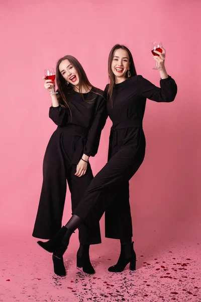 Dos mujeres celebran la fiesta de Año Nuevo divirtiéndose riendo bajo el confeti volador y bebiendo vino . —  Fotos de Stock