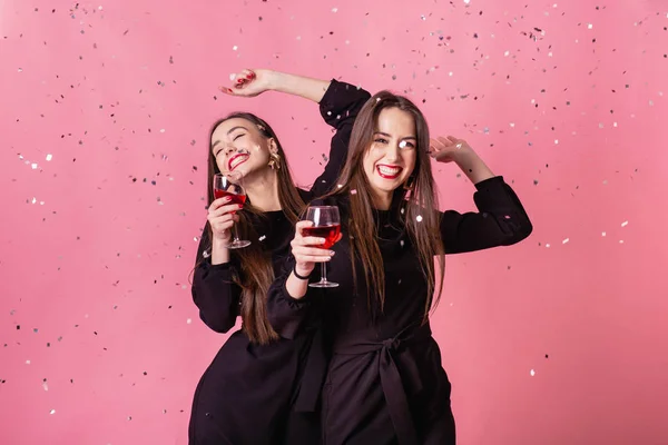Dos mujeres celebran la fiesta de Año Nuevo divirtiéndose riendo bajo el confeti volador y bebiendo vino . —  Fotos de Stock