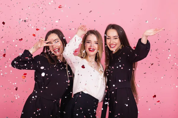 Tres mujeres celebran la fiesta de Año Nuevo divirtiéndose riendo bajo el confeti volador . —  Fotos de Stock