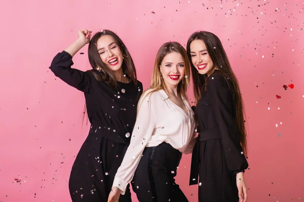 Tres mujeres celebran la fiesta de Año Nuevo divirtiéndose riendo bajo el confeti volador . —  Fotos de Stock