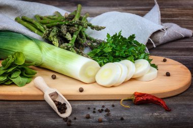 Kuşkonmaz, soğan ve maydanoz, taze bir ahşap zemin üzerine yeşil.