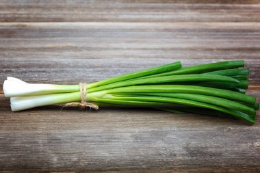 Ahşap bir arka plan üzerinde taze yeşil soğan.