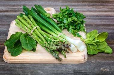 Kuşkonmaz, soğan ve maydanoz, taze bir ahşap zemin üzerine yeşil.