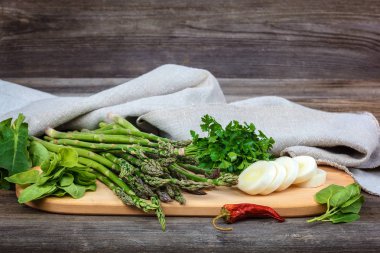 Kuşkonmaz, soğan ve maydanoz, taze bir ahşap zemin üzerine yeşil.