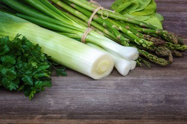Kuşkonmaz, soğan ve maydanoz, taze bir ahşap zemin üzerine yeşil.