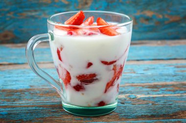 Ahşap arka plan üzerinde bir kasede ekşi kremalı taze çilek.