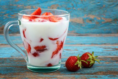 Ahşap arka plan üzerinde bir kasede ekşi kremalı taze çilek.