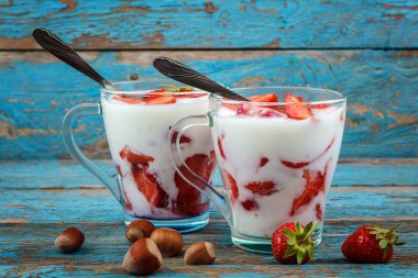 Ahşap arka plan üzerinde bir kasede ekşi kremalı taze çilek.