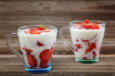 Ahşap arka plan üzerinde bir kasede ekşi kremalı taze çilek.