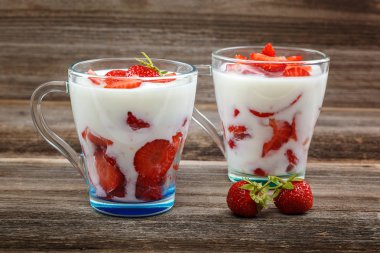 Ahşap arka plan üzerinde bir kasede ekşi kremalı taze çilek.