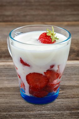 Ahşap arka plan üzerinde bir kasede ekşi kremalı taze çilek.