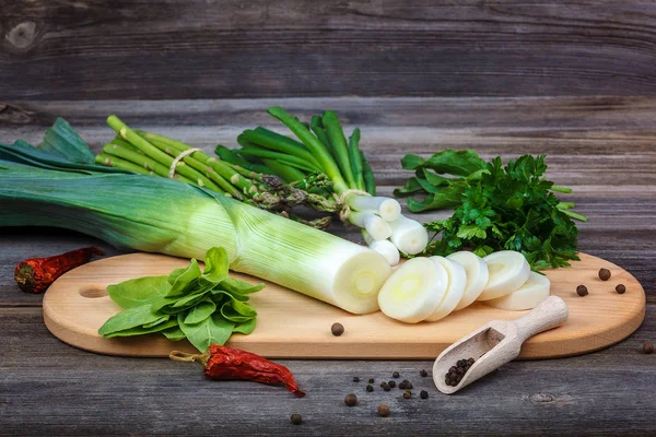 Kuşkonmaz, soğan ve maydanoz, taze bir ahşap zemin üzerine yeşil.