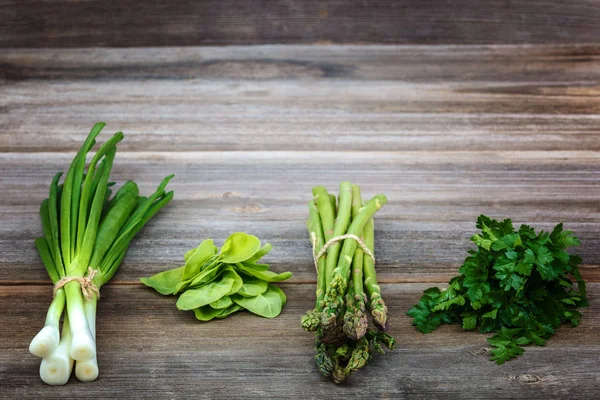 Kuşkonmaz, soğan ve maydanoz, taze bir ahşap zemin üzerine yeşil.
