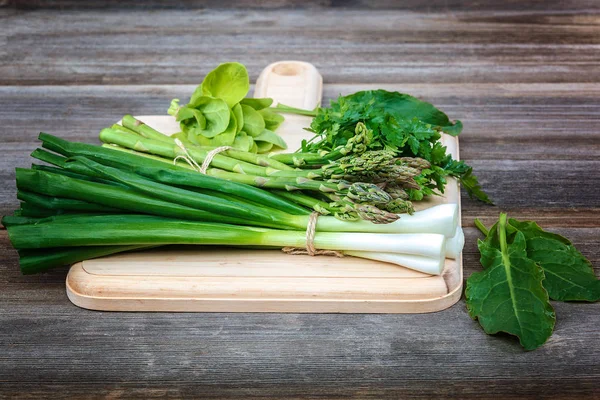 Kuşkonmaz, soğan ve maydanoz, taze bir ahşap zemin üzerine yeşil.