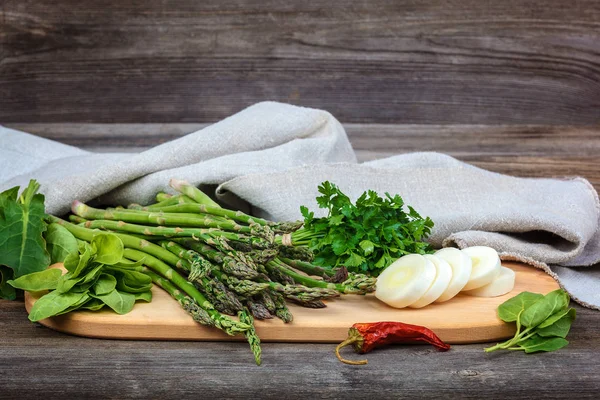 Kuşkonmaz, soğan ve maydanoz, taze bir ahşap zemin üzerine yeşil.