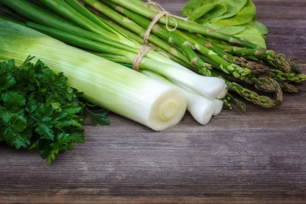 Kuşkonmaz, soğan ve maydanoz, taze bir ahşap zemin üzerine yeşil.