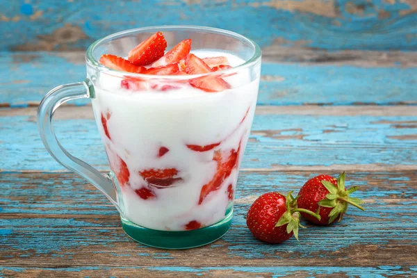 Ahşap arka plan üzerinde bir kasede ekşi kremalı taze çilek.