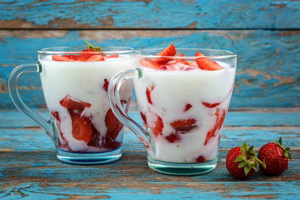 Ahşap arka plan üzerinde bir kasede ekşi kremalı taze çilek.