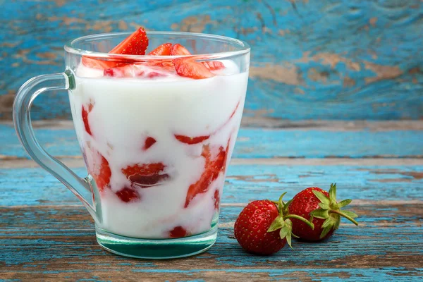 Ahşap arka plan üzerinde bir kasede ekşi kremalı taze çilek.