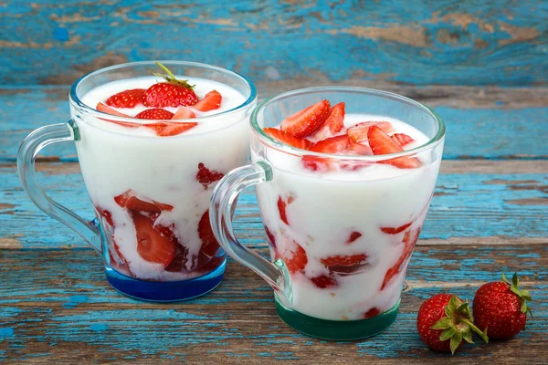 Ahşap arka plan üzerinde bir kasede ekşi kremalı taze çilek.