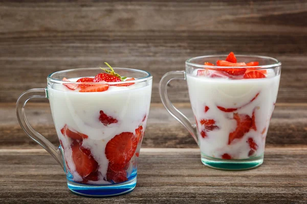 Ahşap arka plan üzerinde bir kasede ekşi kremalı taze çilek.