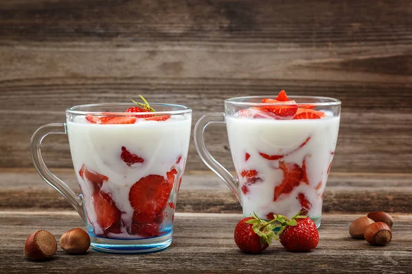 Ahşap arka plan üzerinde bir kasede ekşi kremalı taze çilek.