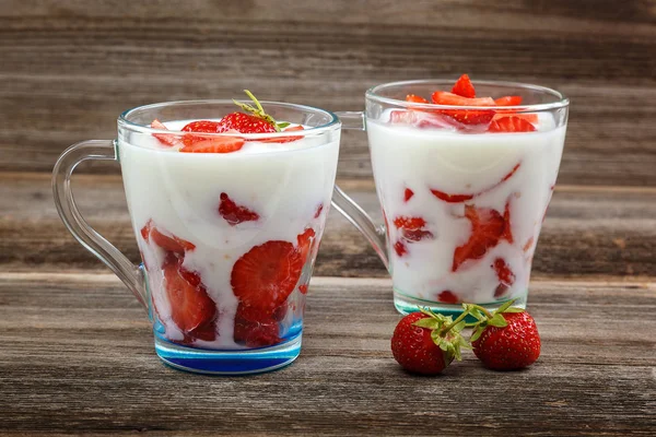 Ahşap arka plan üzerinde bir kasede ekşi kremalı taze çilek.