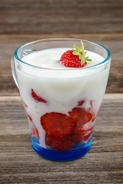 Ahşap arka plan üzerinde bir kasede ekşi kremalı taze çilek.