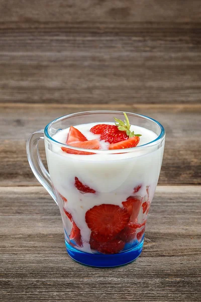 Ahşap arka plan üzerinde bir kasede ekşi kremalı taze çilek.