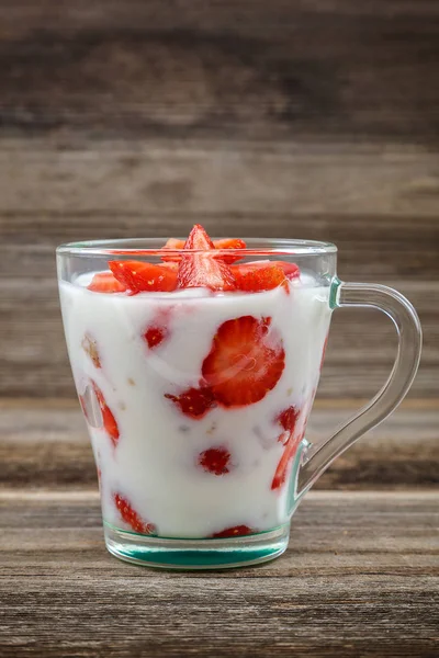 Ahşap arka plan üzerinde bir kasede ekşi kremalı taze çilek.