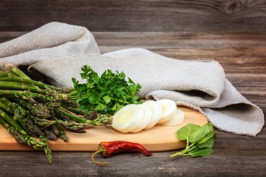 Kuşkonmaz, soğan ve maydanoz, taze bir ahşap zemin üzerine yeşil.