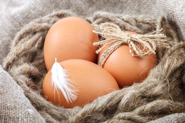 Куриные яйца в плетеной корзине на холсте — стоковое фото
