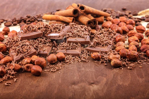 Chokolade fliser, kanel og nødder på en træ baggrund - Stock-foto