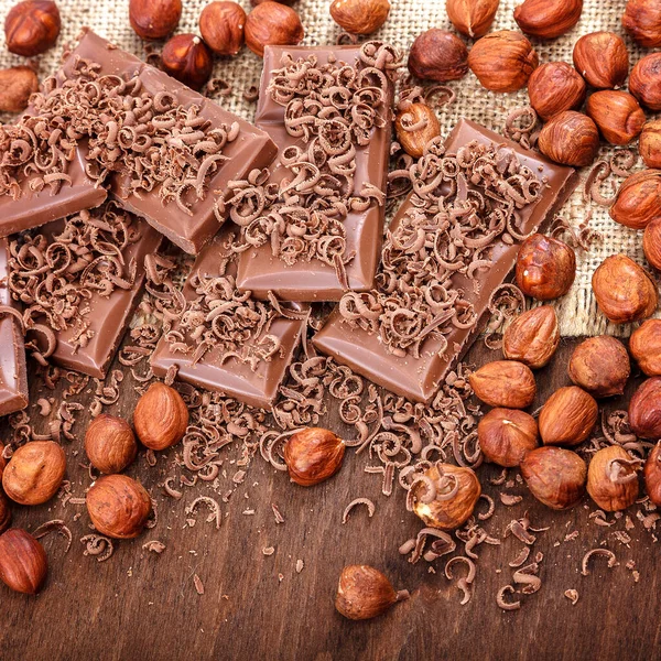 Chokolade fliser, kanel og nødder på en træ baggrund - Stock-foto