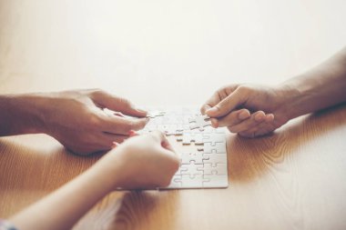 Yüksek açılı görünüş iş adamları el ahşap masa üzerine parçalı bulmaca çözme