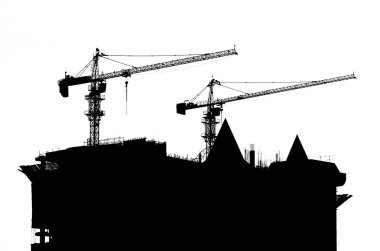 silhouettes of cranes and building construction site