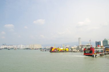 Georgetown, Penang, Malezya 'da arka planda dağ ve bulutlu gökyüzü olan sarı feribot