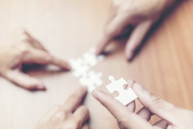 Yüksek açılı görünüş iş adamları el ahşap masa üzerine parçalı bulmaca çözme