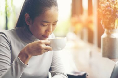 Uzak kapalı masada oturan ve aroma kahve zevk süre seyir büyüleyici dalgın hippi kız. Lezzetli içecek ile boş vakit ve başlangıç hakkında düşünme düşünce iş kadını