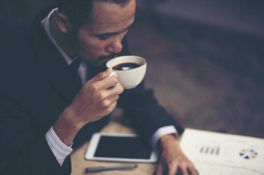 Bir kafede açık havada otururken kahve içen genç bir işadamıportresi