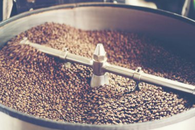 Modern bir kahve kavurma makinesinde taze kavrulmuş aromatik kahve çekirdekleri, vintage filtre görüntüsü