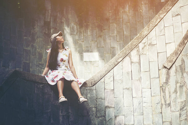 Young girl traveler sitting on circle stairs of a spiral staircase of an underground crossing in tunnel at Fort Canning Park, Singapore