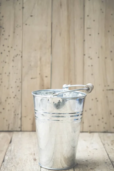 small metal bucket on a wooden background